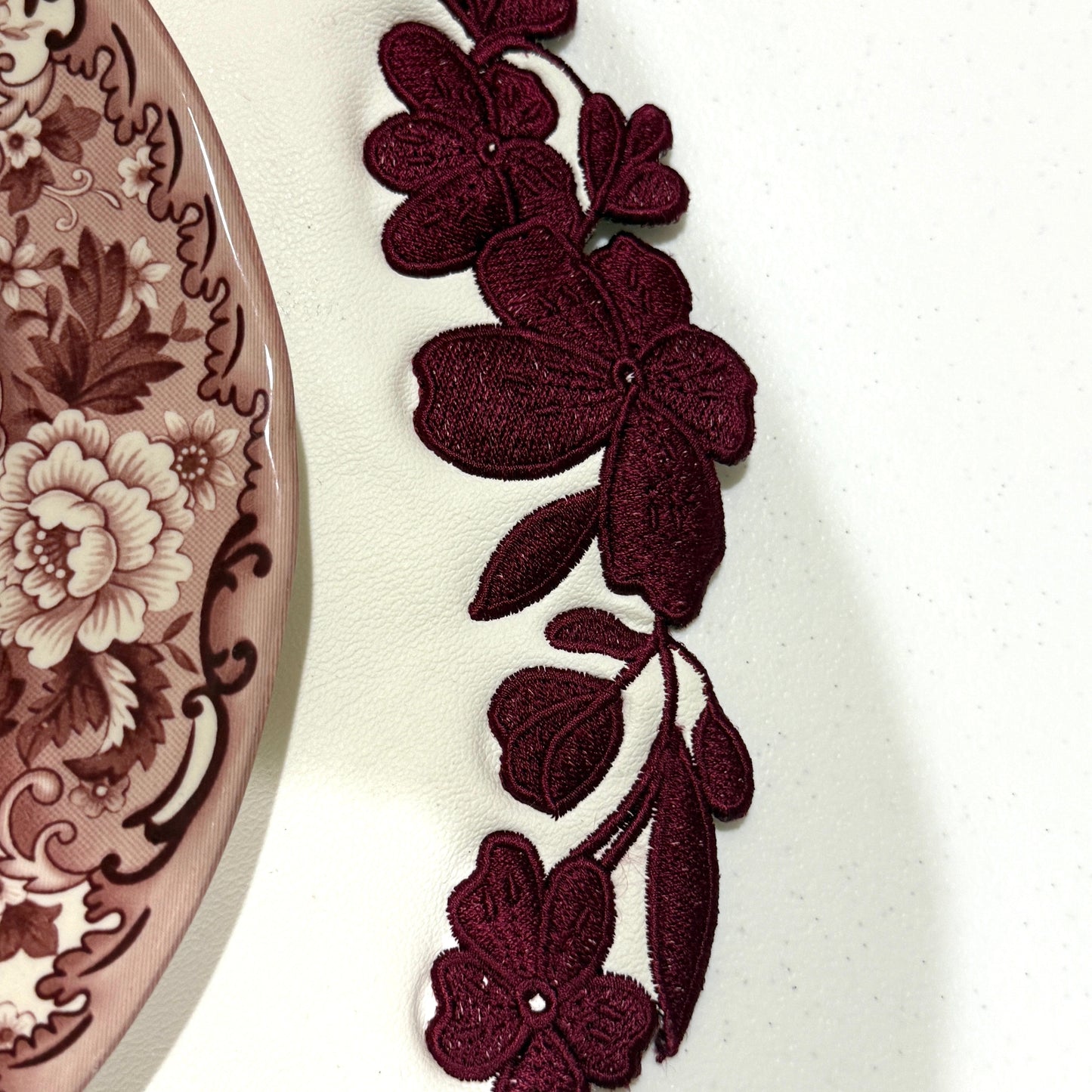 Maroon floral lace trim on a white background