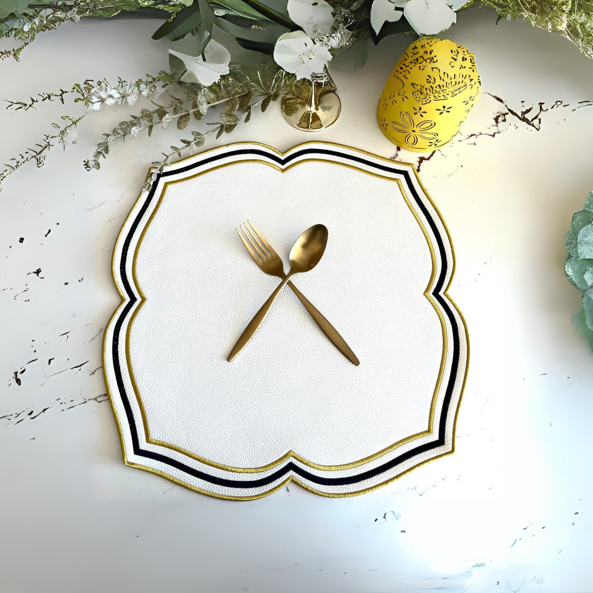 A round faux leather placemat with black and gold detailing, presented on a table with decorative elements around it.