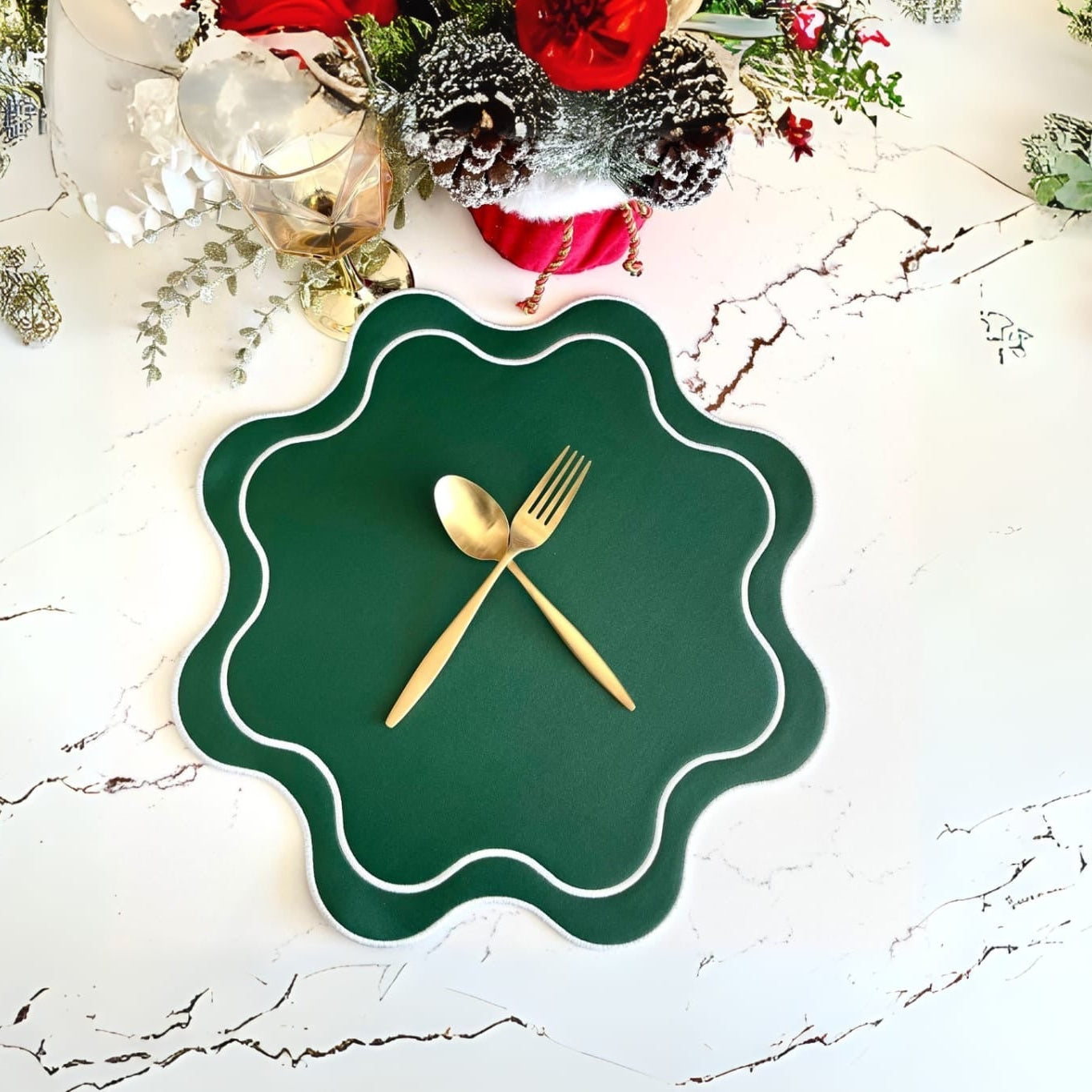 A green faux leather placemat with a round cut-out center, displayed on a table with decorative elements around it. It has a white and gold pattern along the edge and is accompanied by a pair of golden utensils.
