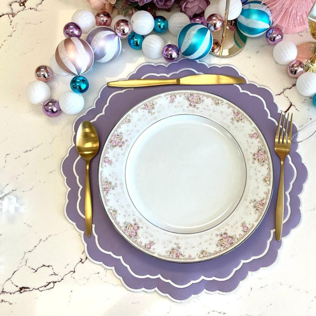 Decorative table setting with a plate, cutlery, and colorful beads on a marble surface.