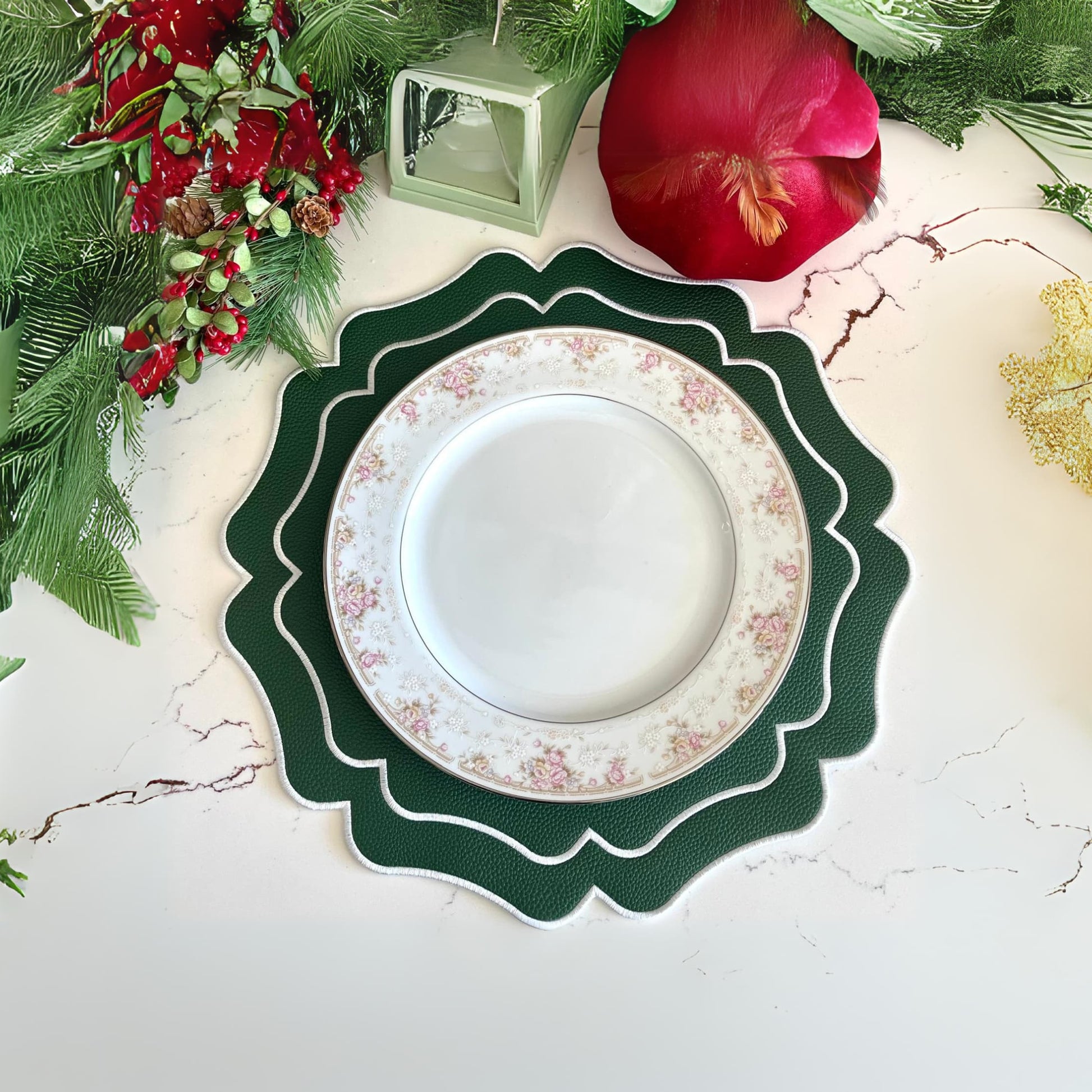 A green faux leather placemat is displayed on a table with a decorative plate on top of it, surrounded by a festive arrangement of red berries and green foliage.