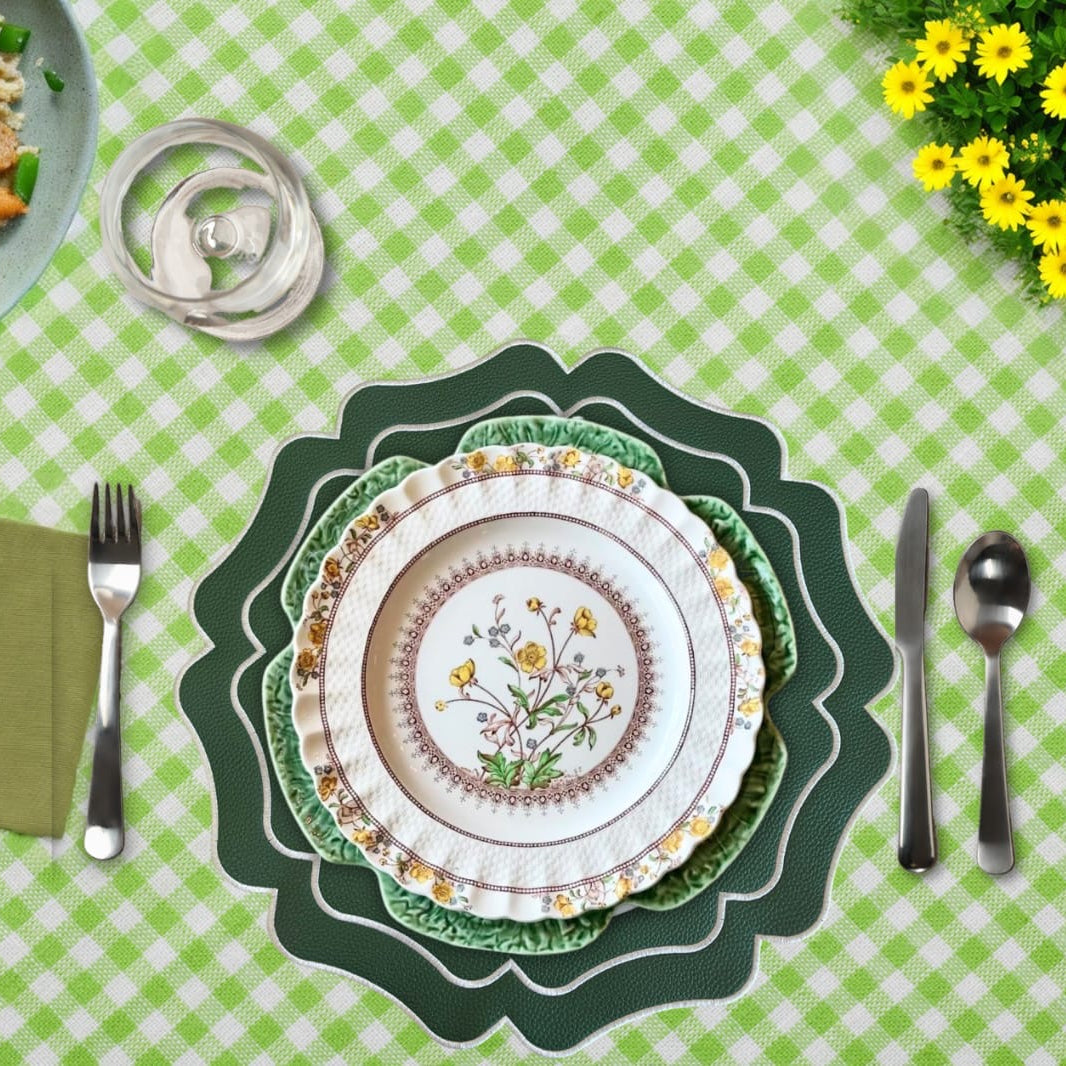 Decorative floral plate on a green checkered tablecloth with cutlery and flowers.