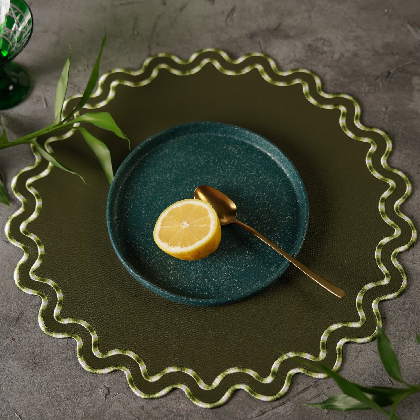 Green plate with a lemon and spoon on a textured surface