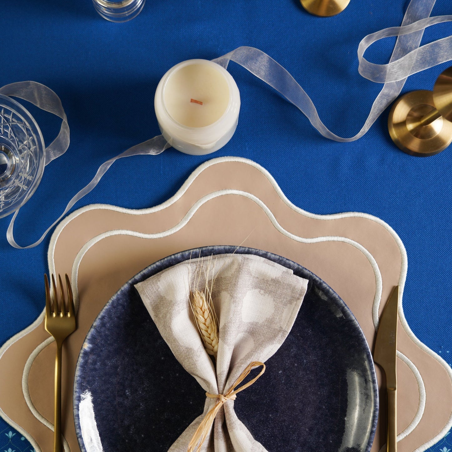 Dining table setting with plates, napkin, and cutlery on a blue tablecloth.