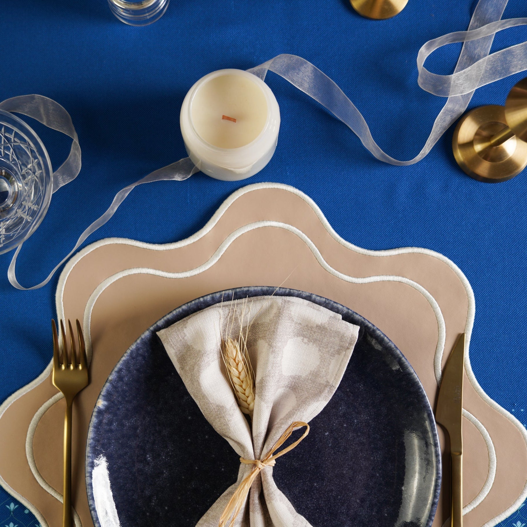 Dining table setting with plates, napkin, and cutlery on a blue tablecloth.