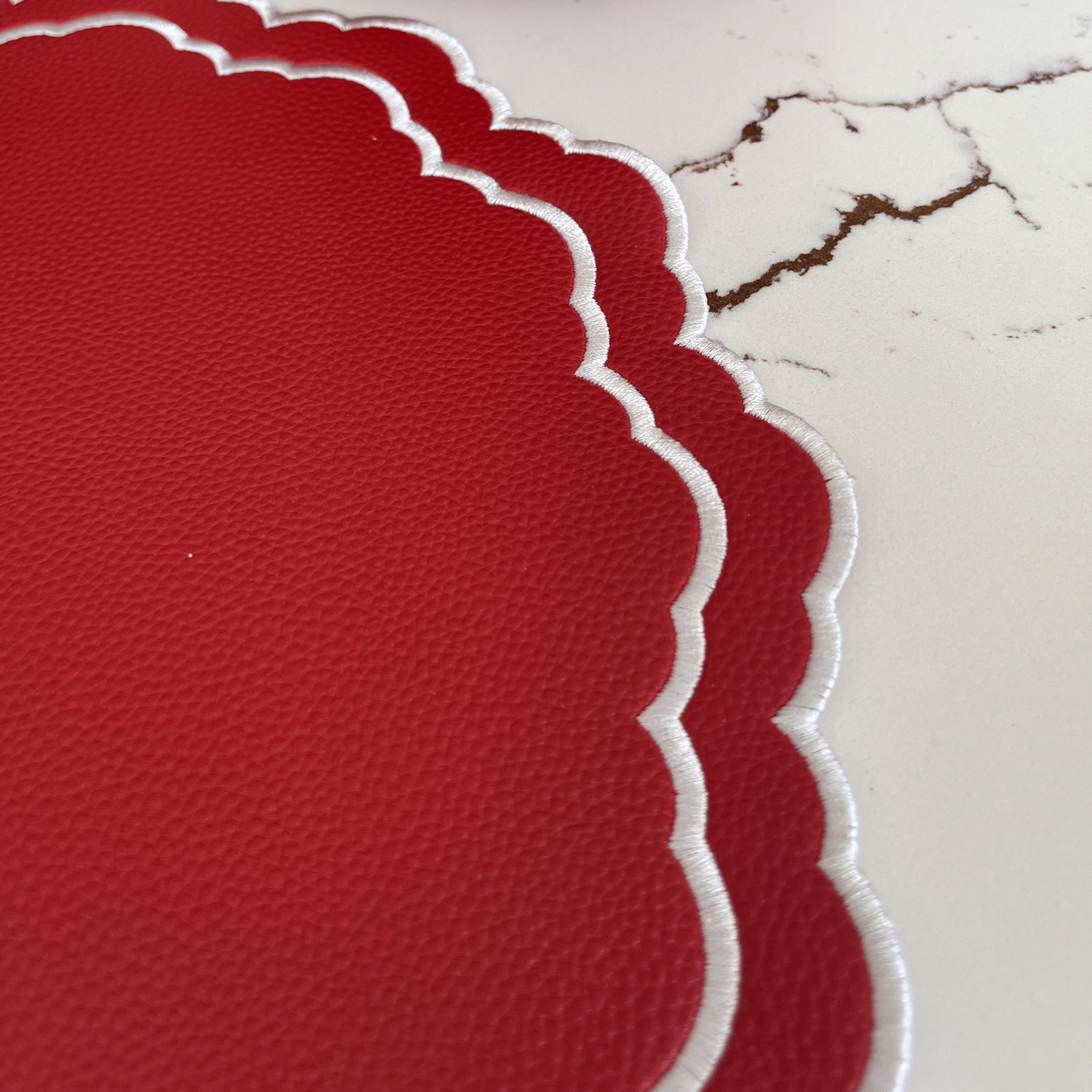 Red scalloped placemats on a marble surface