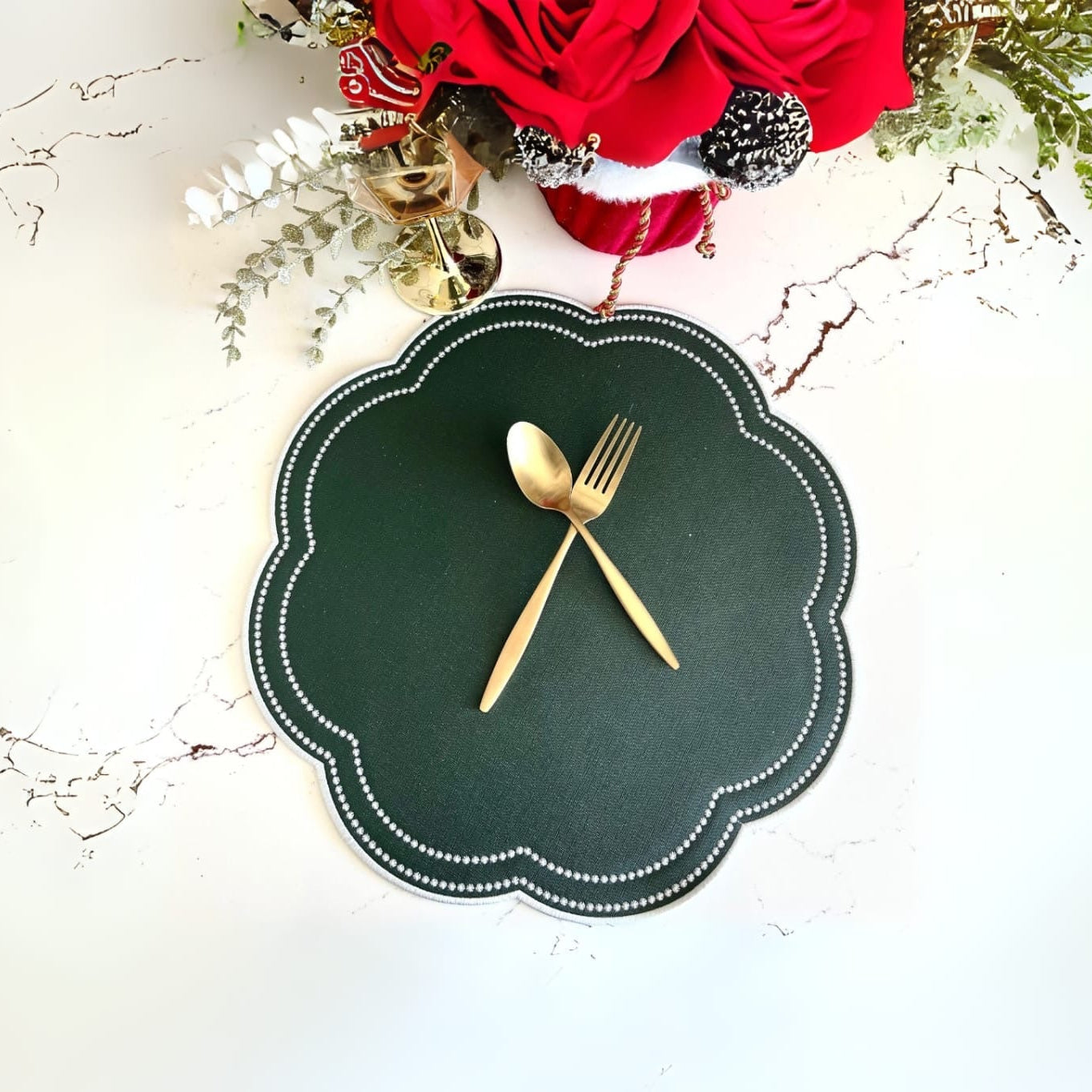 A round green faux leather placemat with a decorative edge, featuring a Fork and Knife placed on top, presented against a white background with a festive decoration in the corner.