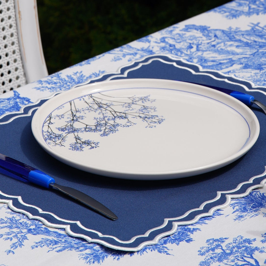 Table setting with blue and white patterned tablecloth and place mat.