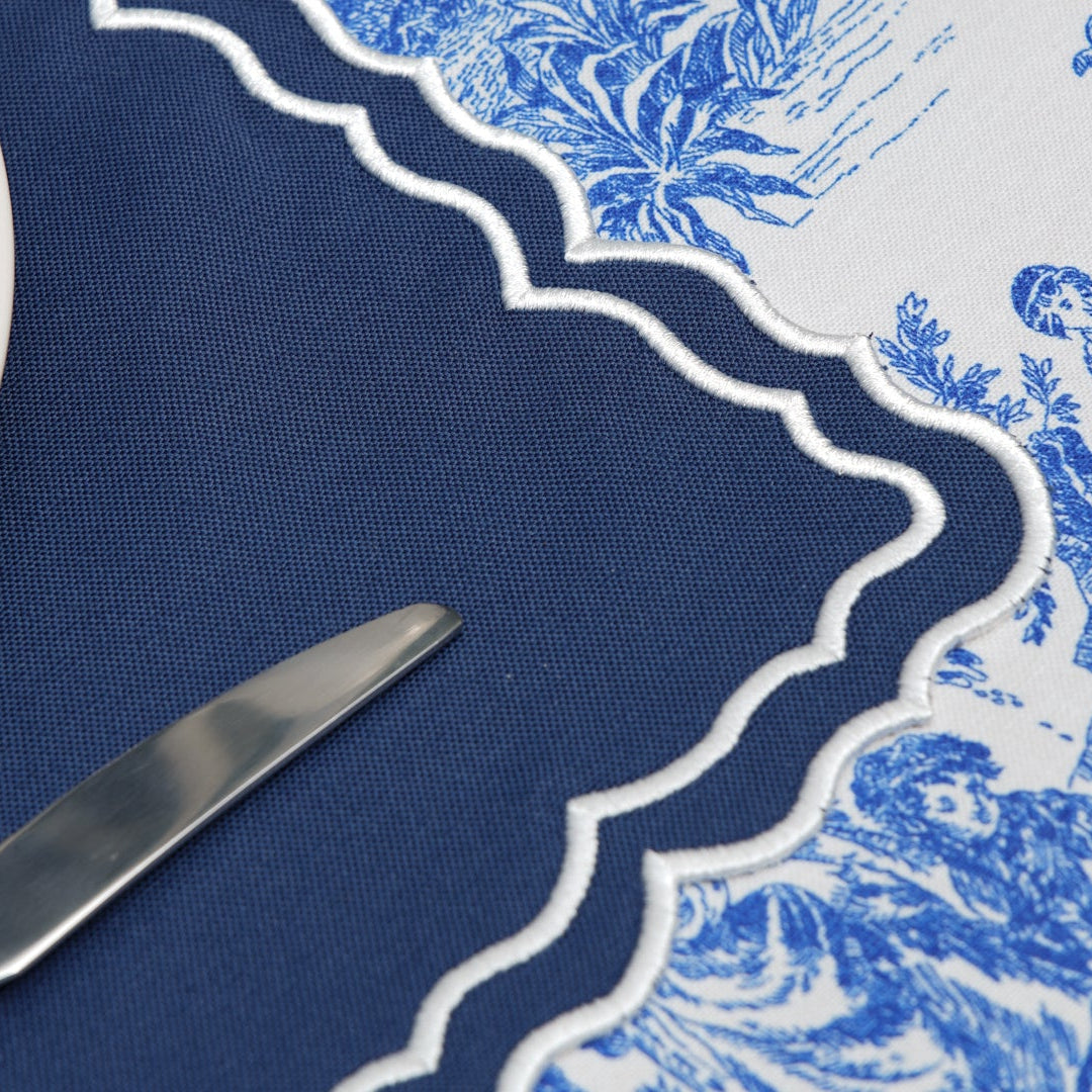 Table setting with blue and white patterned tablecloth and knife on dark blue placemat.