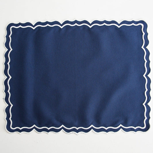 Navy blue placemat with white scalloped edge on a light gray background
