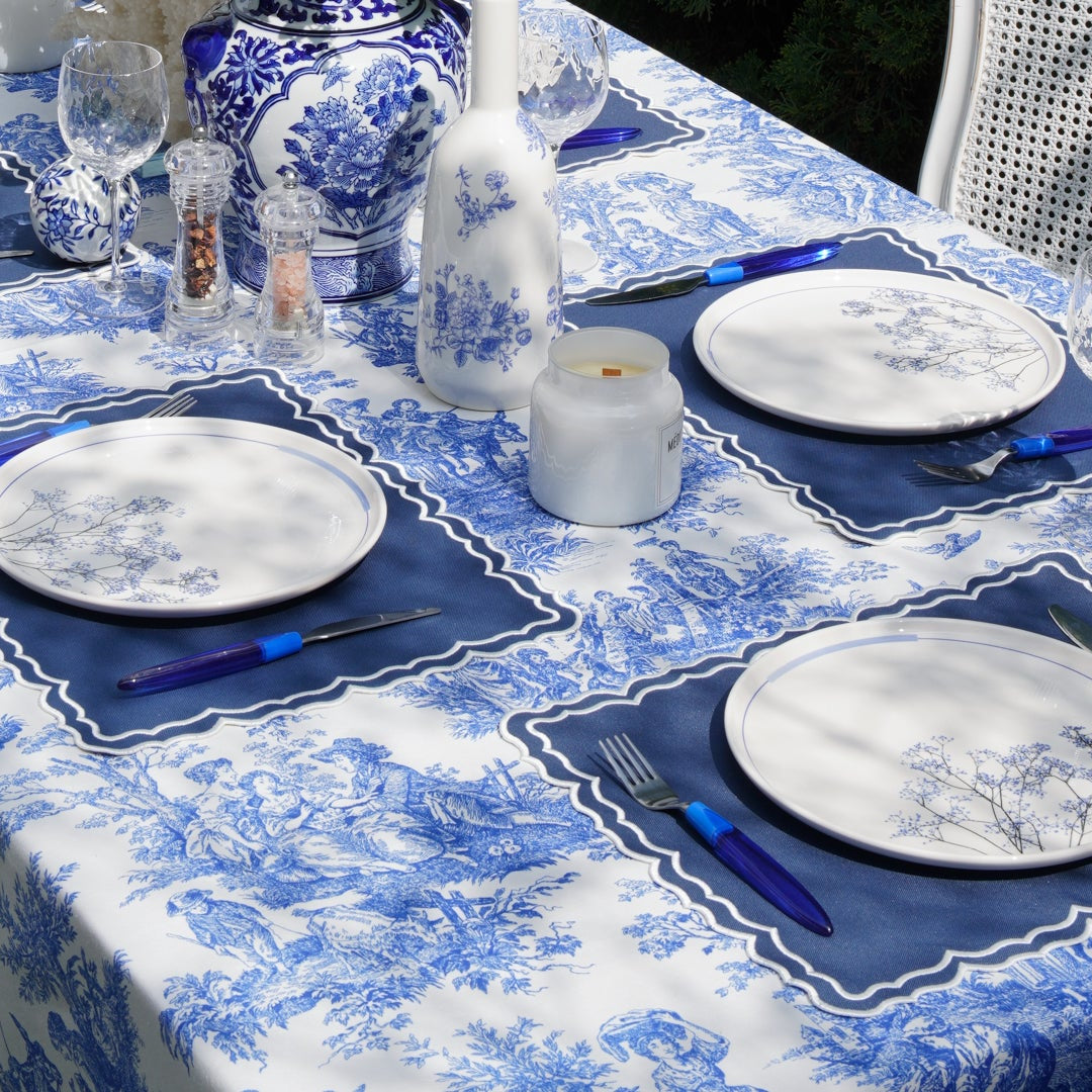 Set table with blue and white patterned tablecloth and plates.