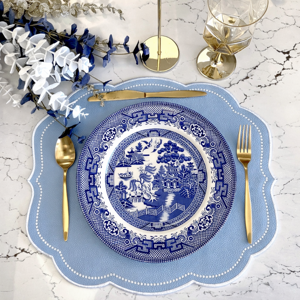 Decorative blue and white plate with gold cutlery on a marble surface