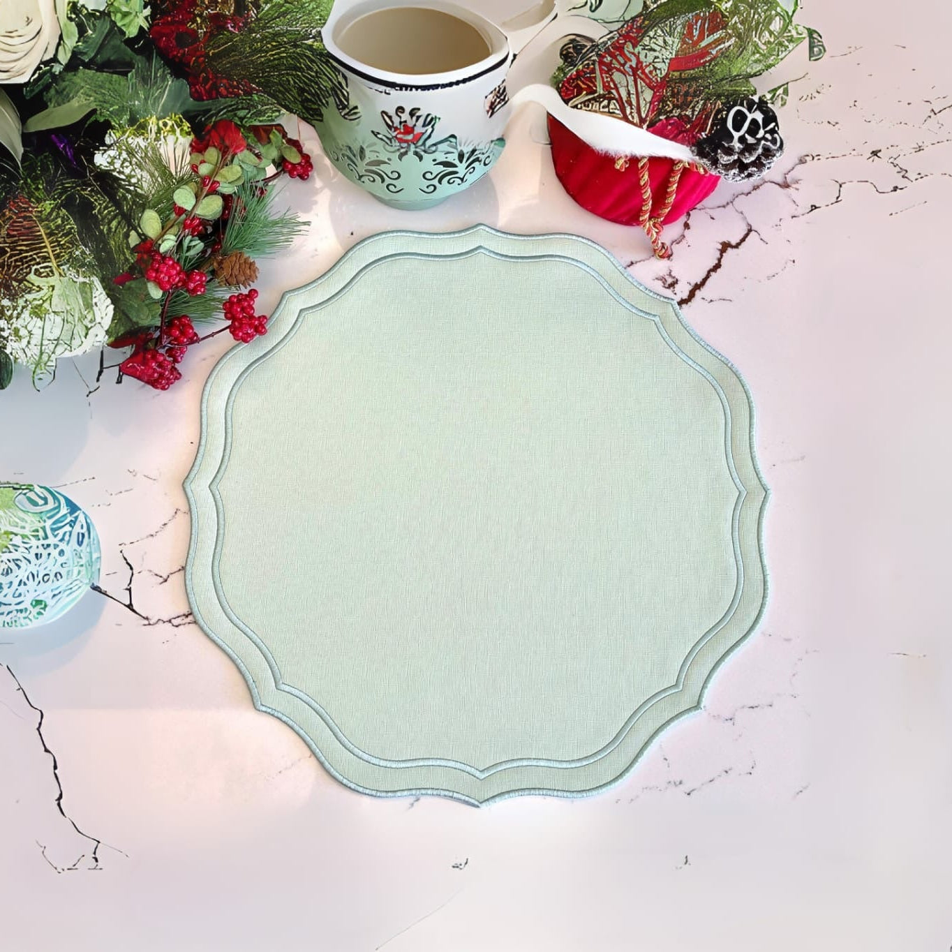 A light green faux leather placemat with a scalloped edge design, displayed on a table with a floral arrangement and a red and white checkered napkin.
