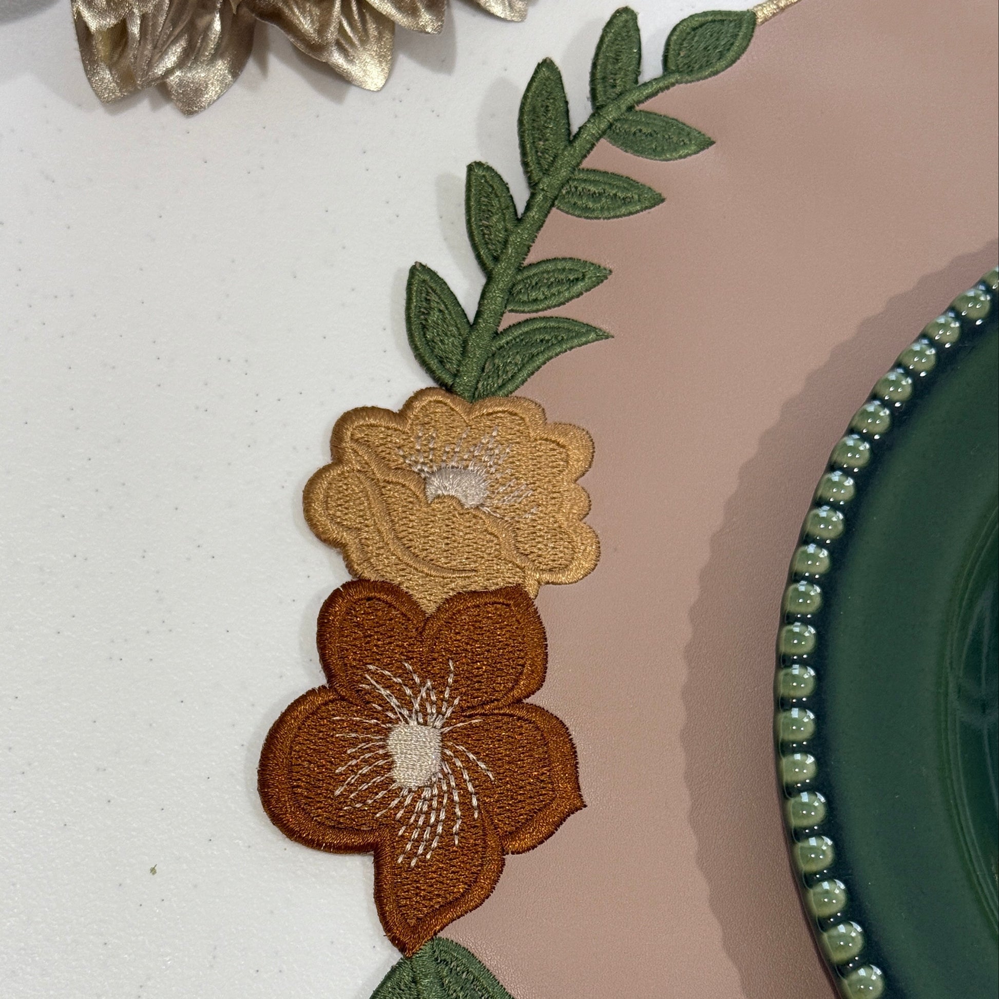 Embroidered floral design on a fabric with a green border.