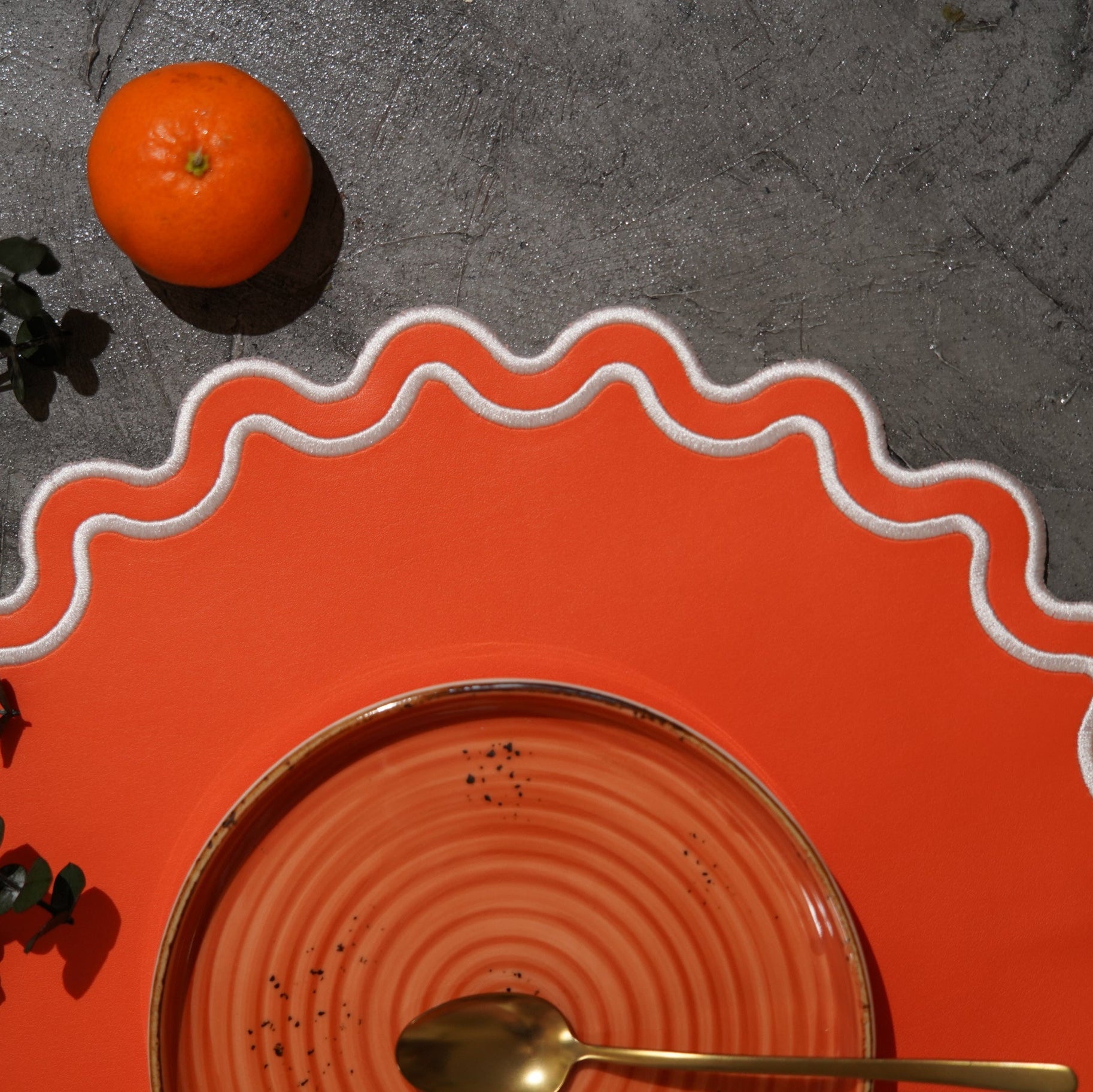 Orange plate with wavy edge on a dark gray surface