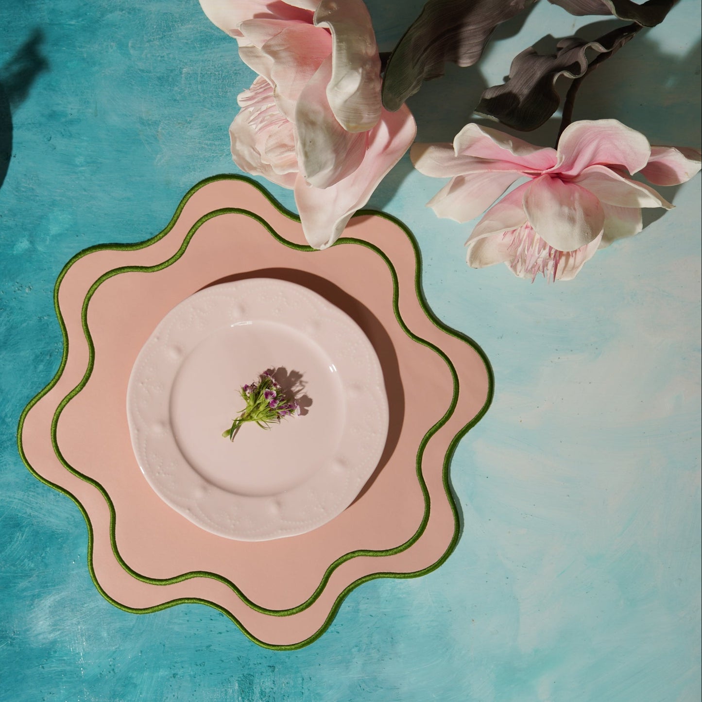 Decorative pink plate with floral design on a blue surface