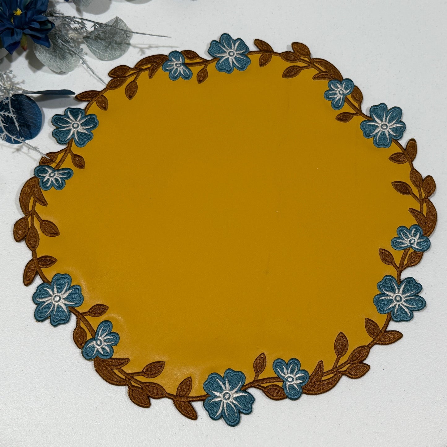 Round placemat with floral border on a white background