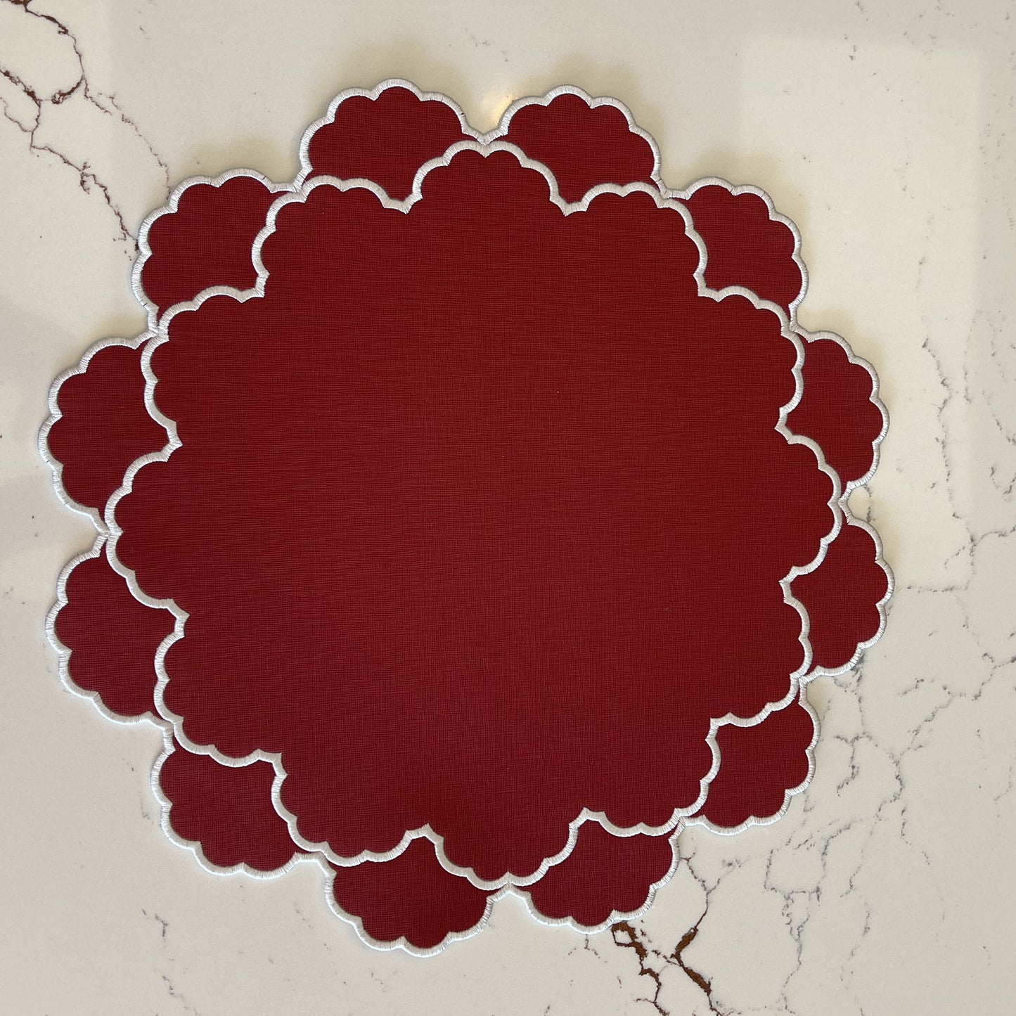 Red scalloped circular object on a textured beige background