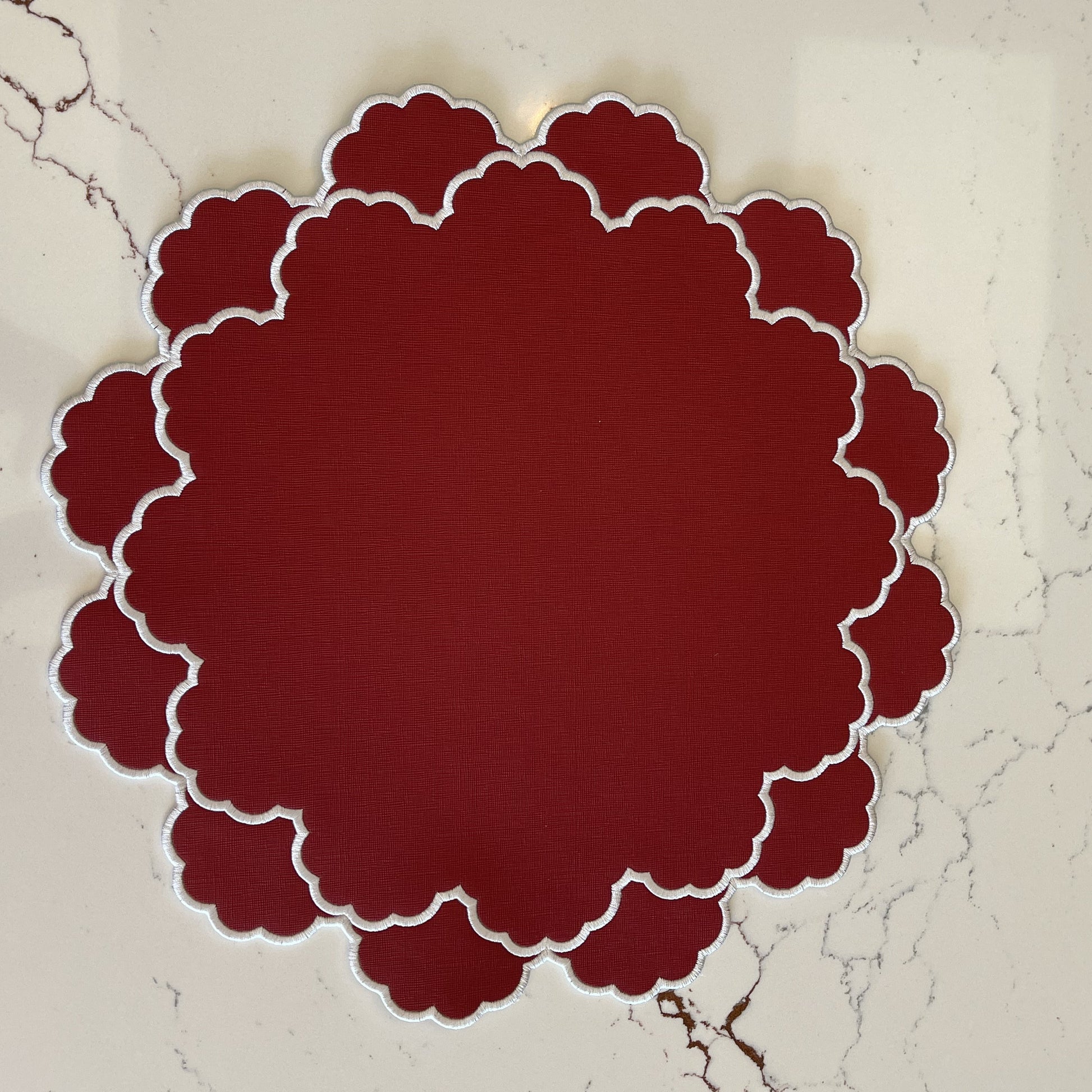 Red scalloped circular object on a textured beige background