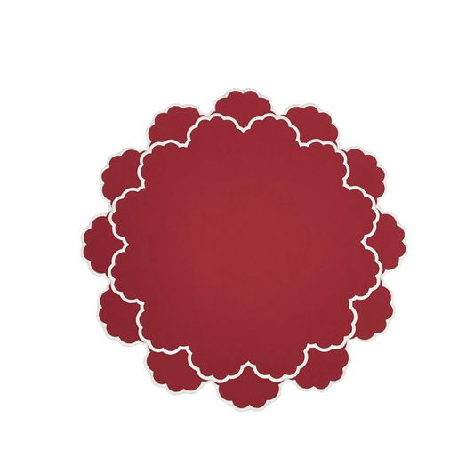 A red faux leather placemat with a scalloped edge design and white stitching around the border.