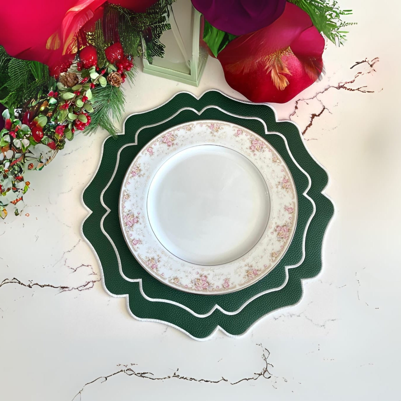 Decorative plate with floral design on a green scalloped edge, surrounded by flowers and greenery.
