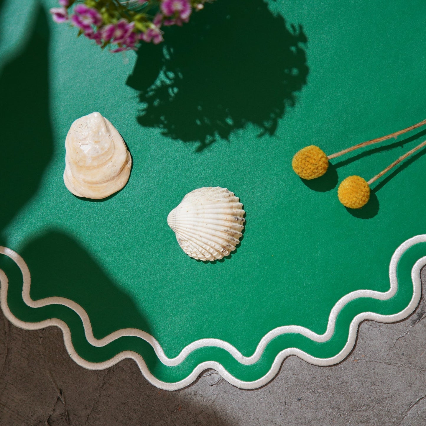 Two shells and yellow flowers on a green surface with decorative edge