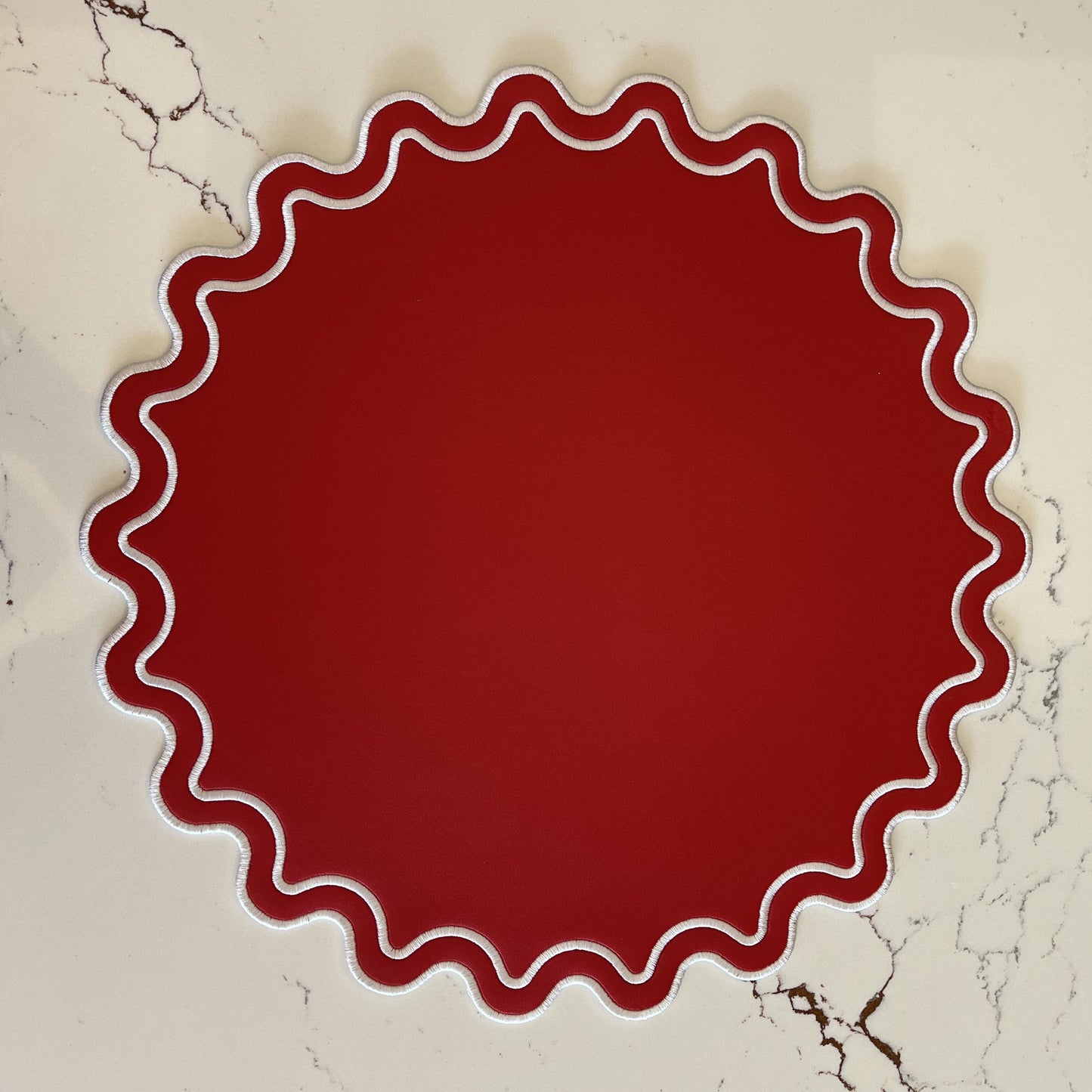 Red circular object with wavy edge on a marble background