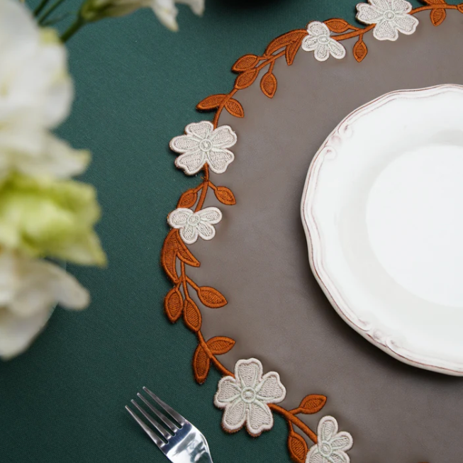 Decorative floral placemat on a table with a white plate and fork.