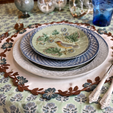 Decorative table setting with a patterned tablecloth, plates, and glasses.