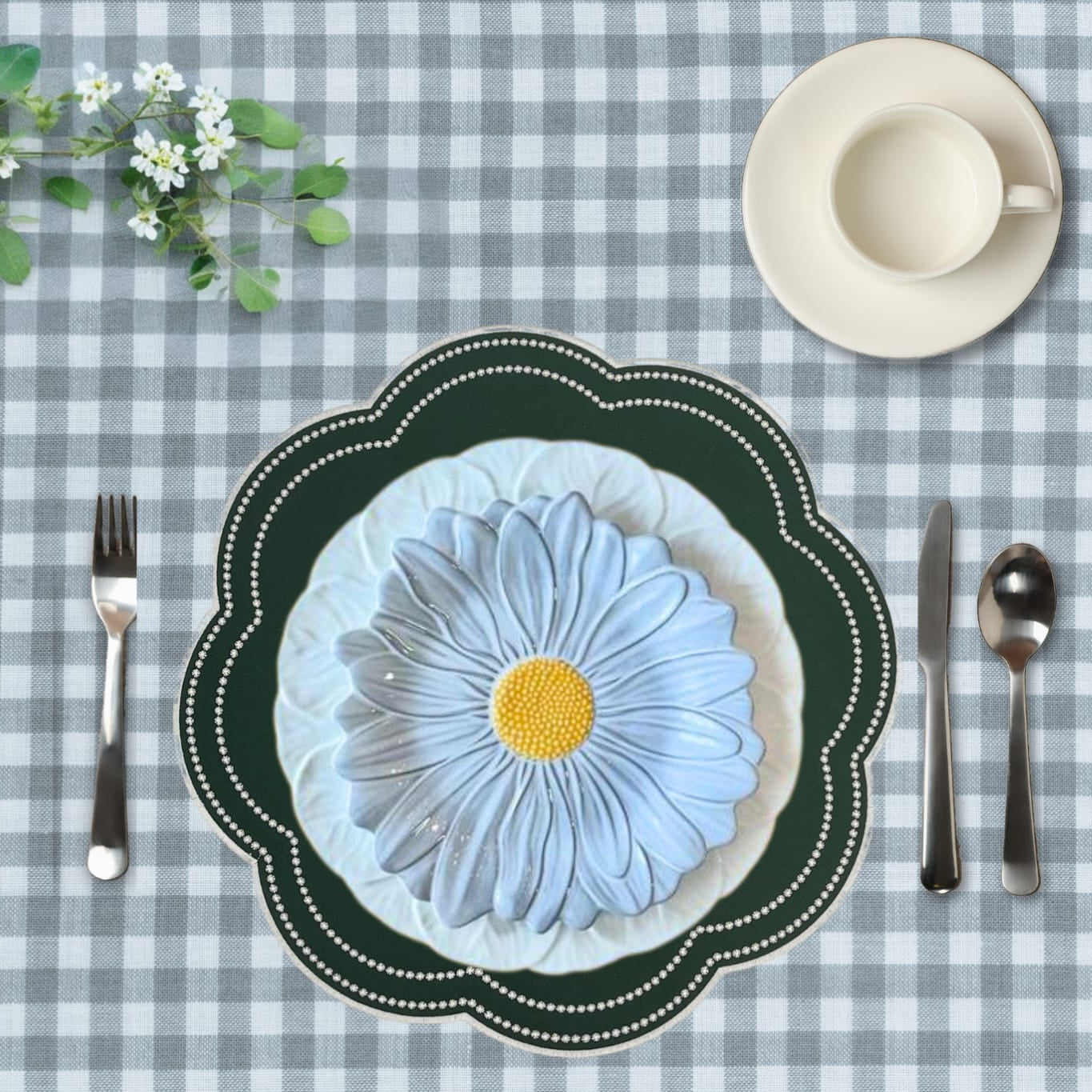 Placemat with floral design on a checkered tablecloth, featuring cutlery and a cup.