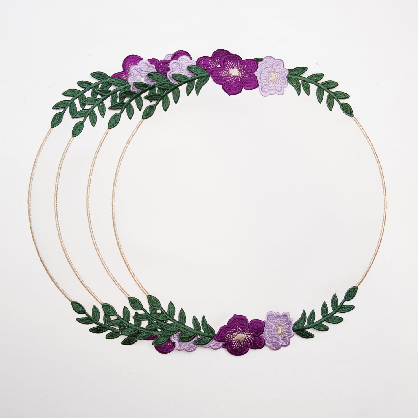 Gold circular hoop with purple flowers and green leaves on a white background